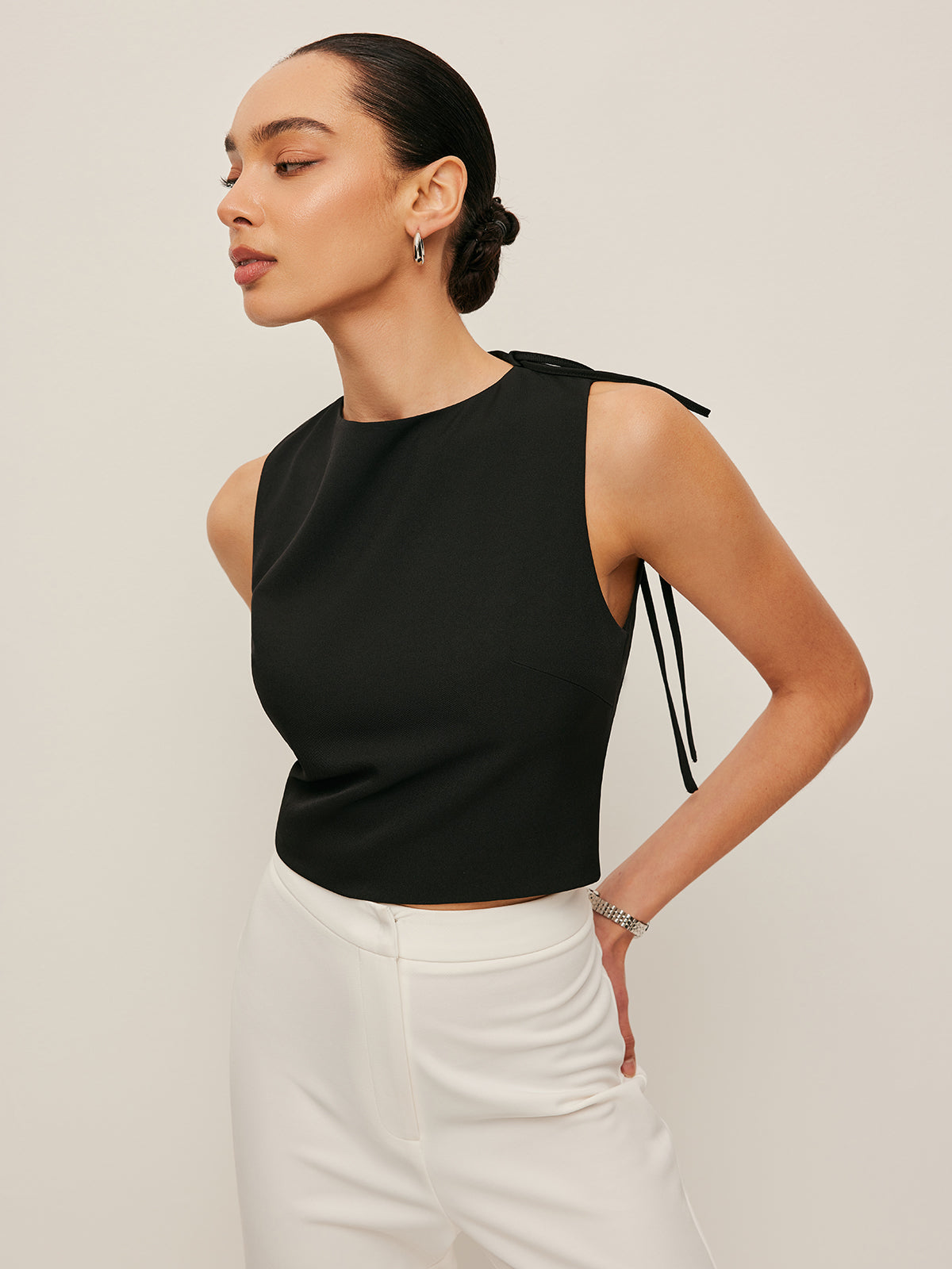 Backless blouse featuring a stylish tie neck detail, sleek sleeveless design, and made from smooth woven fabric, perfect for chic summer outings. 1