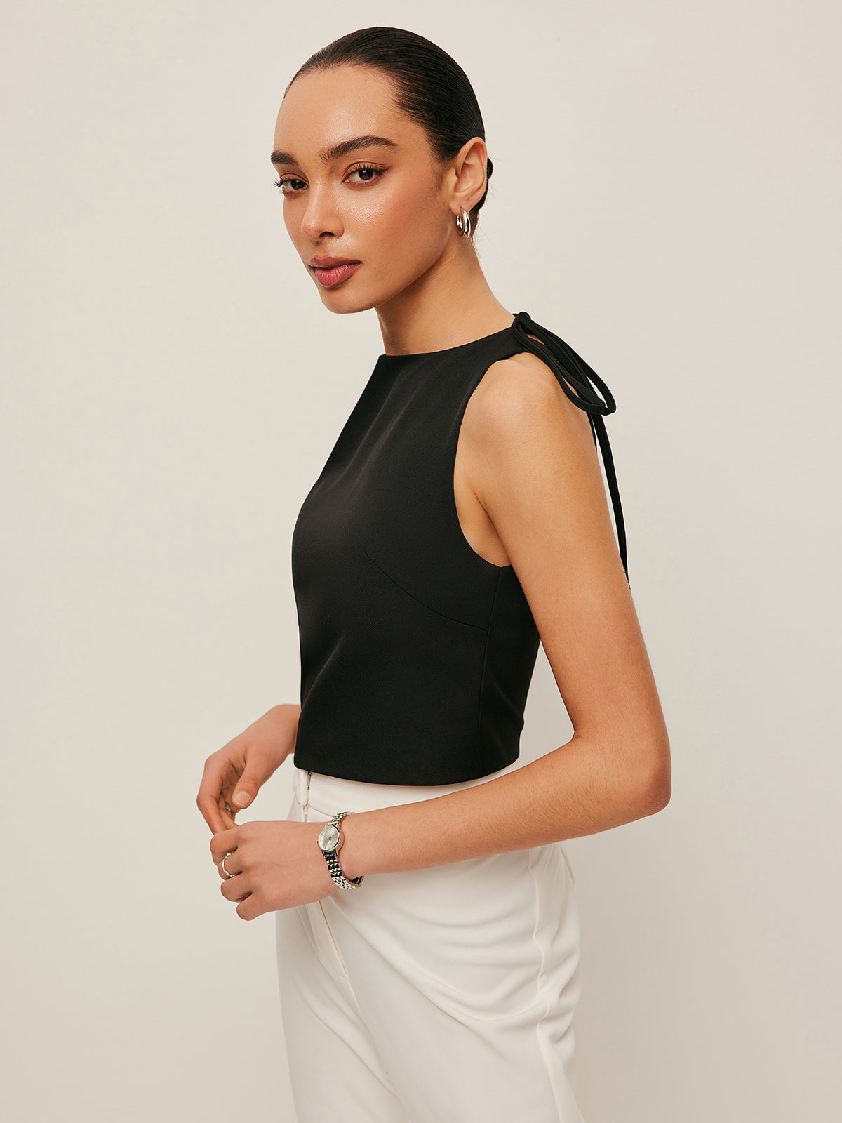 Backless blouse featuring a stylish tie neck detail, sleek sleeveless design, and made from smooth woven fabric, perfect for chic summer outings. 3