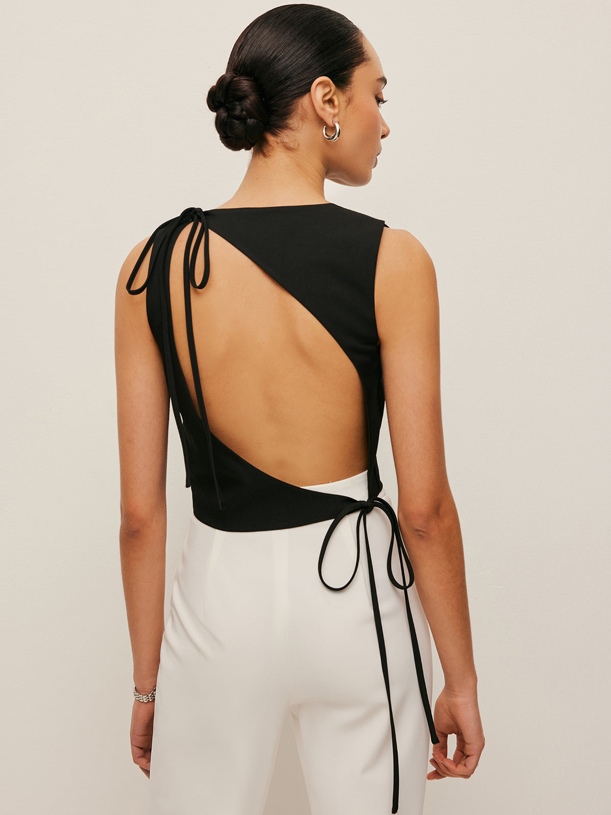 Backless blouse featuring a stylish tie neck detail, sleek sleeveless design, and made from smooth woven fabric, perfect for chic summer outings. 4