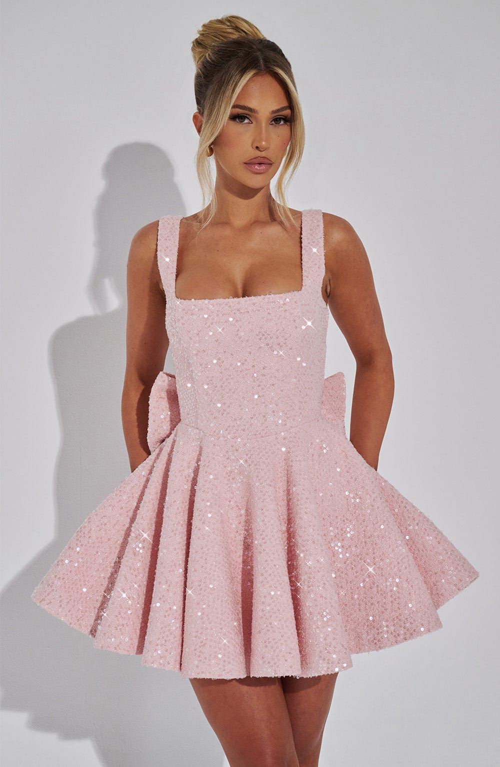 Sequin mini dress with flared skirt and back bow detail, perfect for wedding guests and cocktail parties. 0