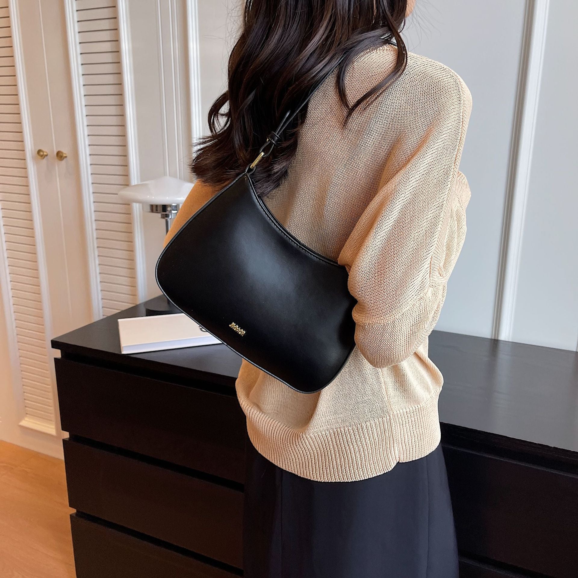 Shoulder bag with adjustable strap, featuring a minimalist curved design in vegan leather, perfect for everyday use and compact storage. 1