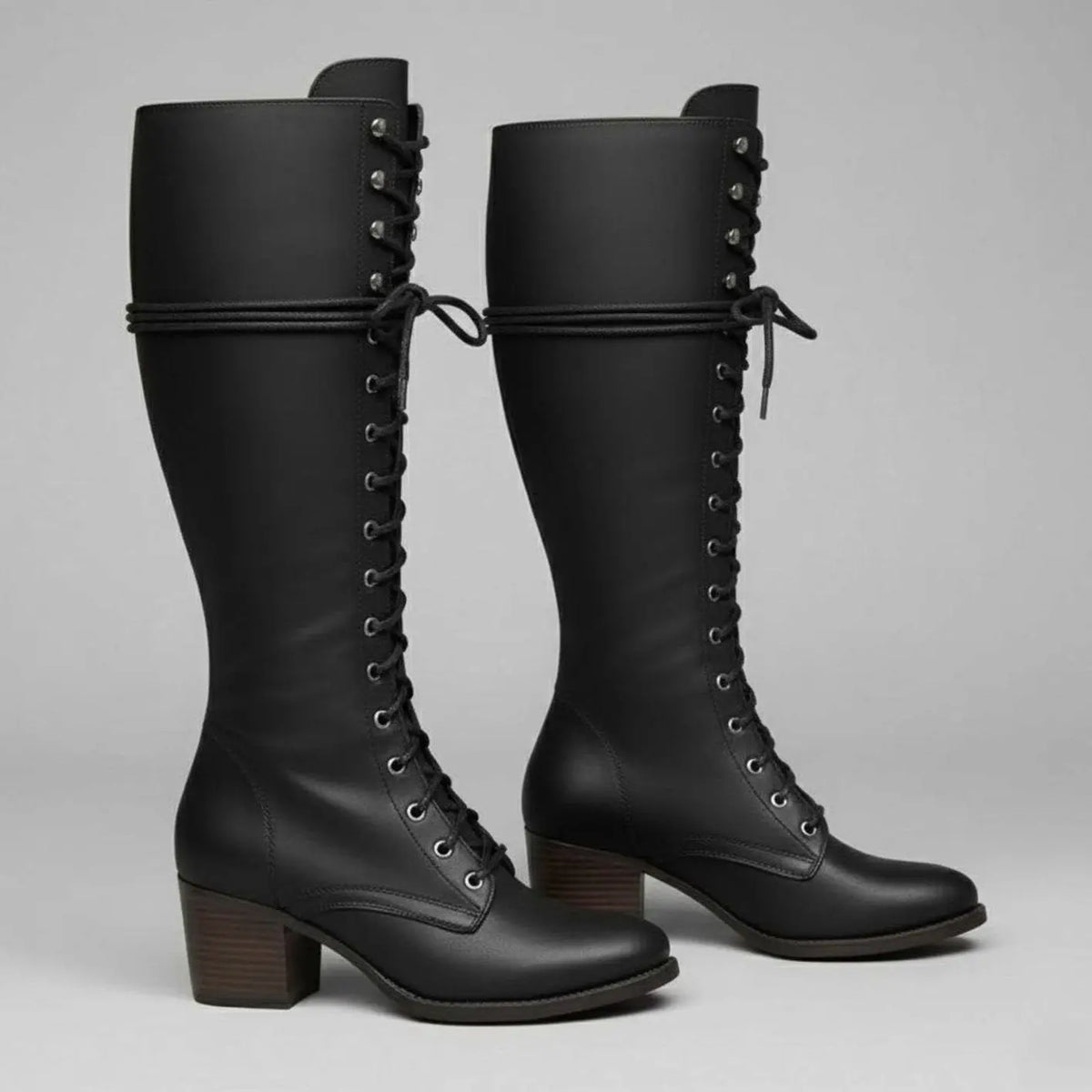 Women's black faux leather knee-high boots featuring a lace-up front, block heel, and stylish stud detail. 1