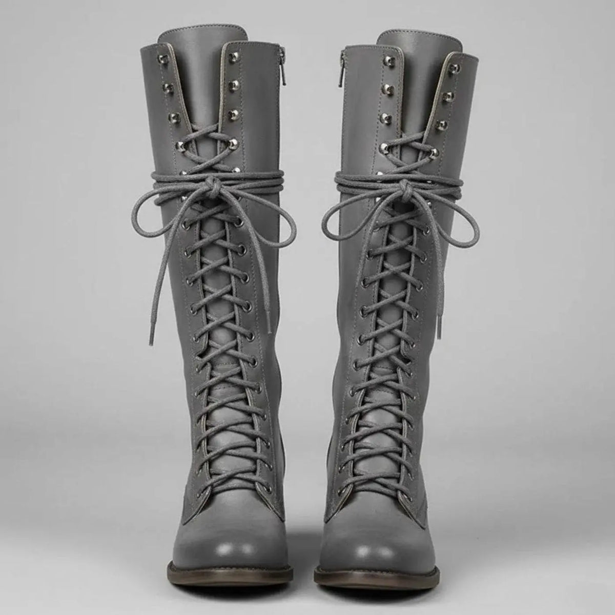 Women's black faux leather knee-high boots featuring a lace-up front, block heel, and stylish stud detail. 2