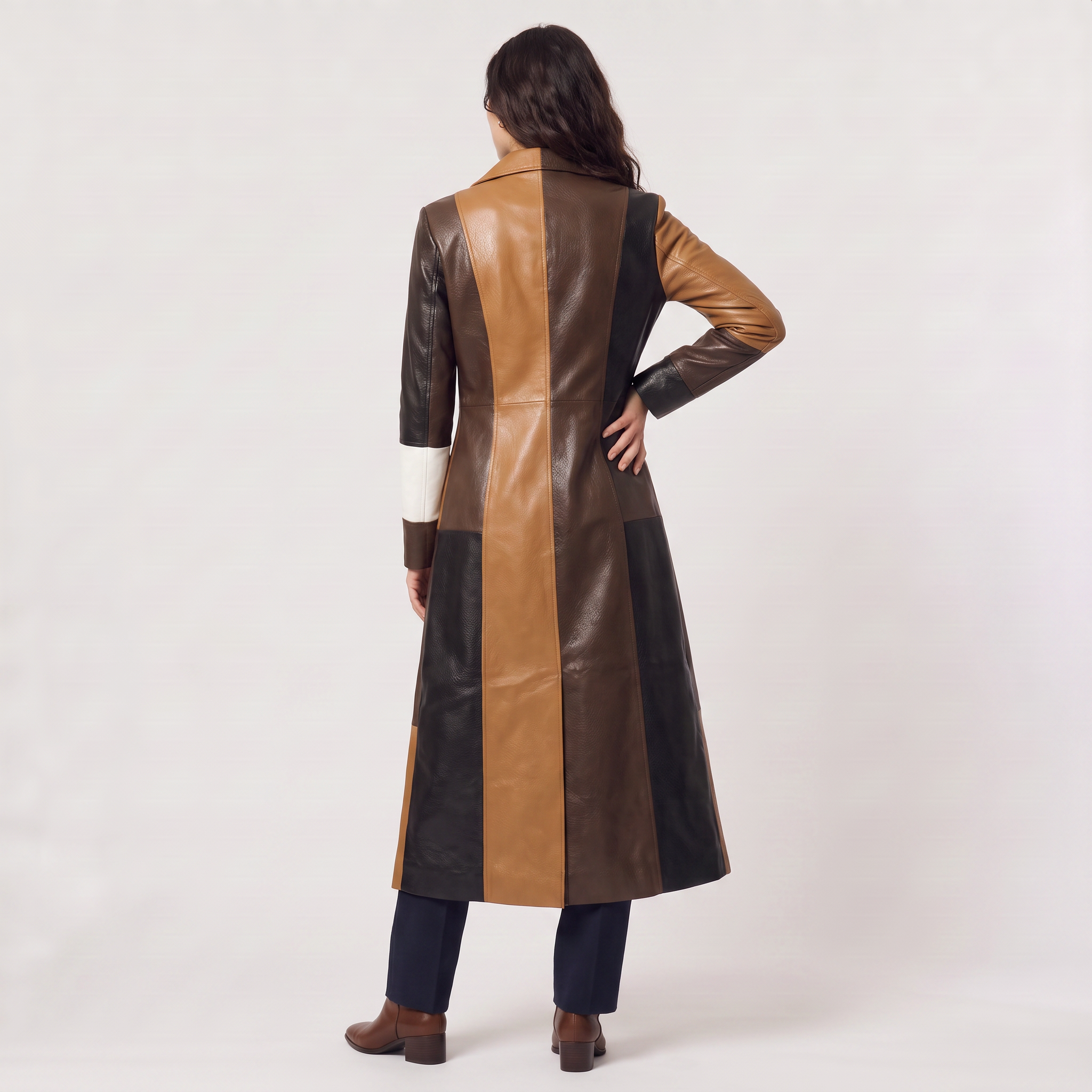 Women's trench coat featuring a stylish patchwork design in faux leather, showcasing a long structured silhouette in brown, black, and white colors. 4