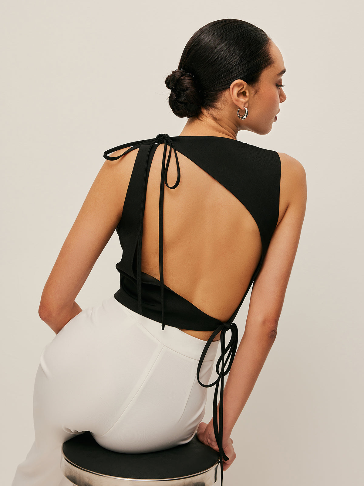 Backless blouse featuring a stylish tie neck detail, sleek sleeveless design, and made from smooth woven fabric, perfect for chic summer outings. 0