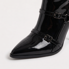 Black knee high boots featuring a sleek patent finish, inner zip closure, and stylish buckled straps, designed with elegant stiletto heels for women. 2