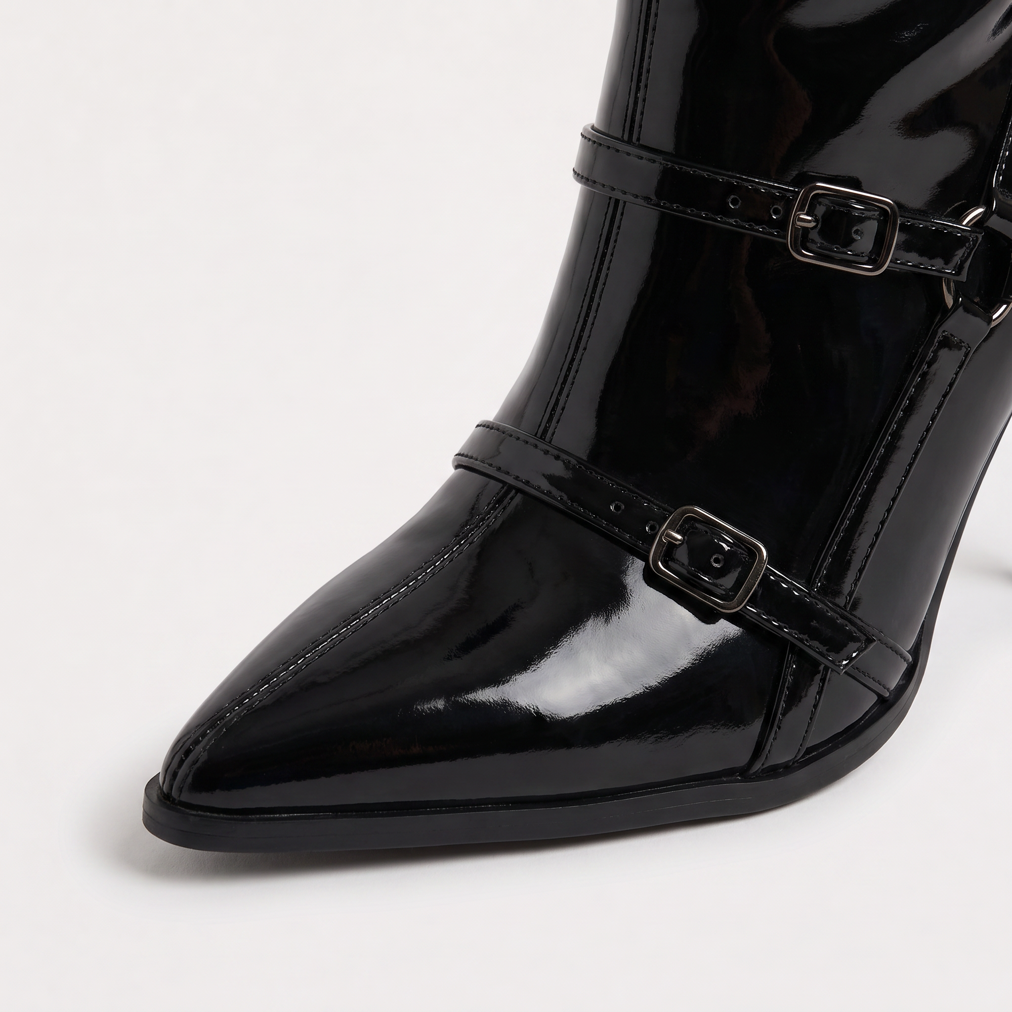Black knee high boots featuring a sleek patent finish, inner zip closure, and stylish buckled straps, designed with elegant stiletto heels for women. 2