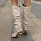 Black knee high boots featuring studded straps and a block heel, crafted from slouchy vegan leather for a stylish and comfortable fit for women. 3