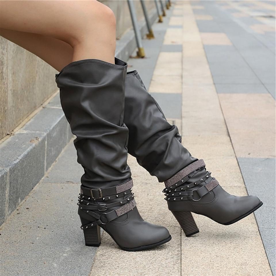 Black knee high boots featuring studded straps and a block heel, crafted from slouchy vegan leather for a stylish and comfortable fit for women. 6