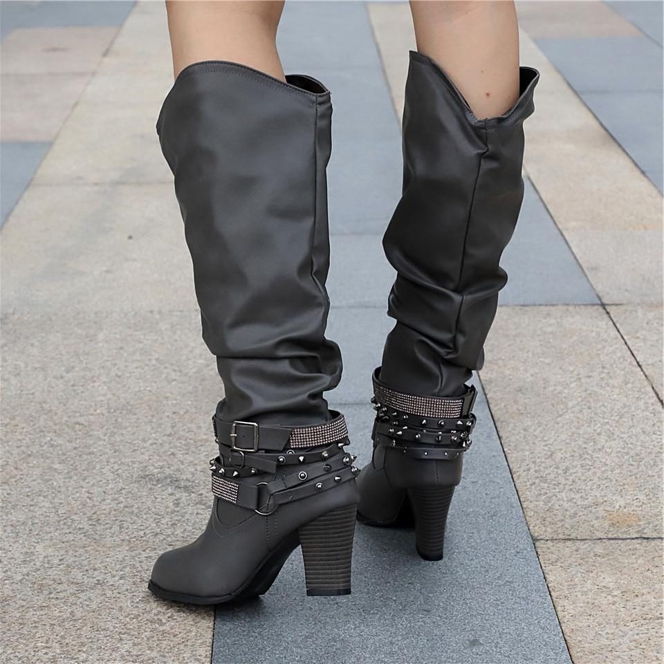 Black knee high boots featuring studded straps and a block heel, crafted from slouchy vegan leather for a stylish and comfortable fit for women. 7