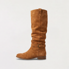Knee high black boots for women featuring a slouch silhouette and buckled ankle tab, crafted from vegan materials with a low stacked heel. 0