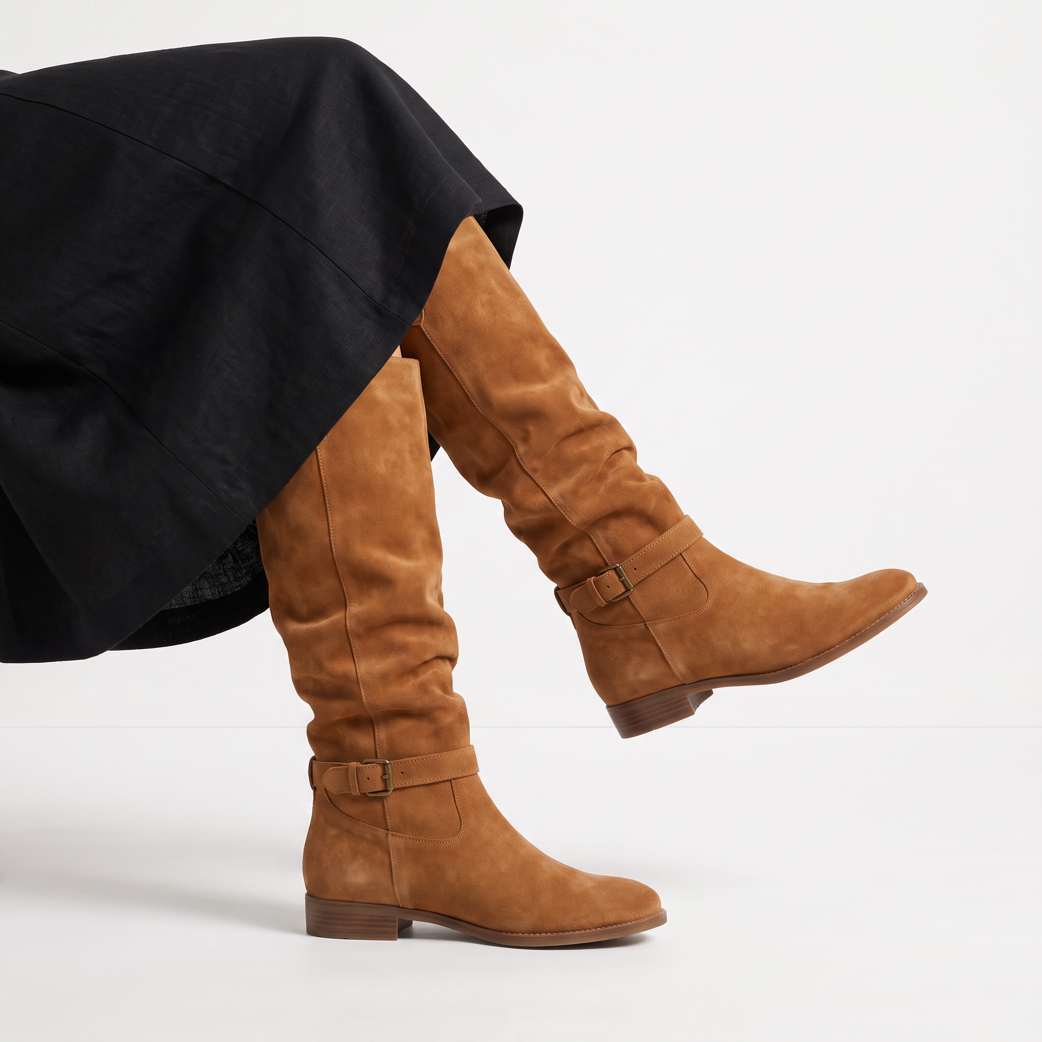 Knee high black boots for women featuring a slouch silhouette and buckled ankle tab, crafted from vegan materials with a low stacked heel. 4