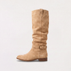 Knee high black boots for women featuring a slouch silhouette and buckled ankle tab, crafted from vegan materials with a low stacked heel. 5