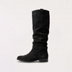 Knee high black boots for women featuring a slouch silhouette and buckled ankle tab, crafted from vegan materials with a low stacked heel. 7