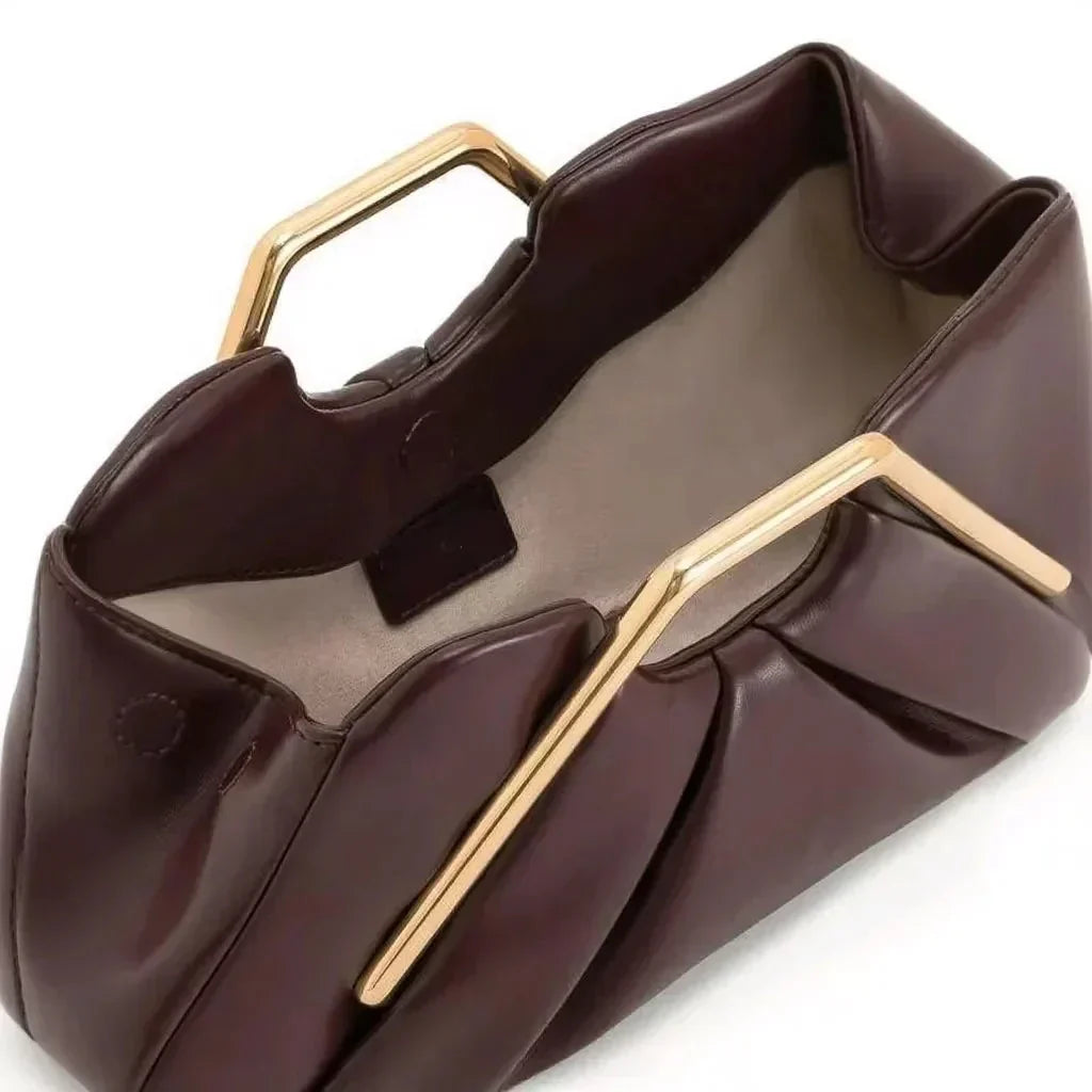 Stylish leather clutch bag featuring a gold handle, origami-inspired design, and a spacious interior made from high-quality microfiber leather. 2