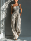 Linen blend jumpsuit featuring adjustable tie straps, square neckline, and wide-leg design in beige and white stripes. 0