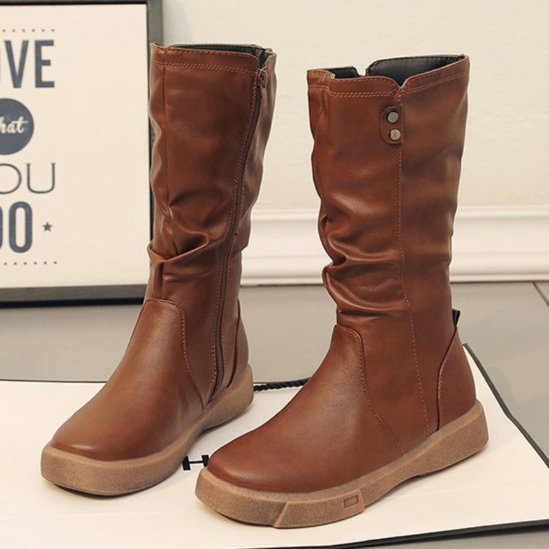 Mid calf boots for women featuring a chunky flat sole and side zip, designed with a stylish slouchy silhouette in vegan leather. 1