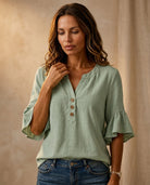 Ruffle blouse with V-neckline and decorative buttons, showcasing a feminine elegant design in soft fabric, perfect for stylish casual or formal wear. 1
