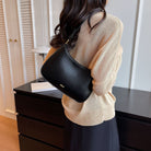 Shoulder bag with adjustable strap, featuring a minimalist curved design in vegan leather, perfect for everyday use and compact storage. 1
