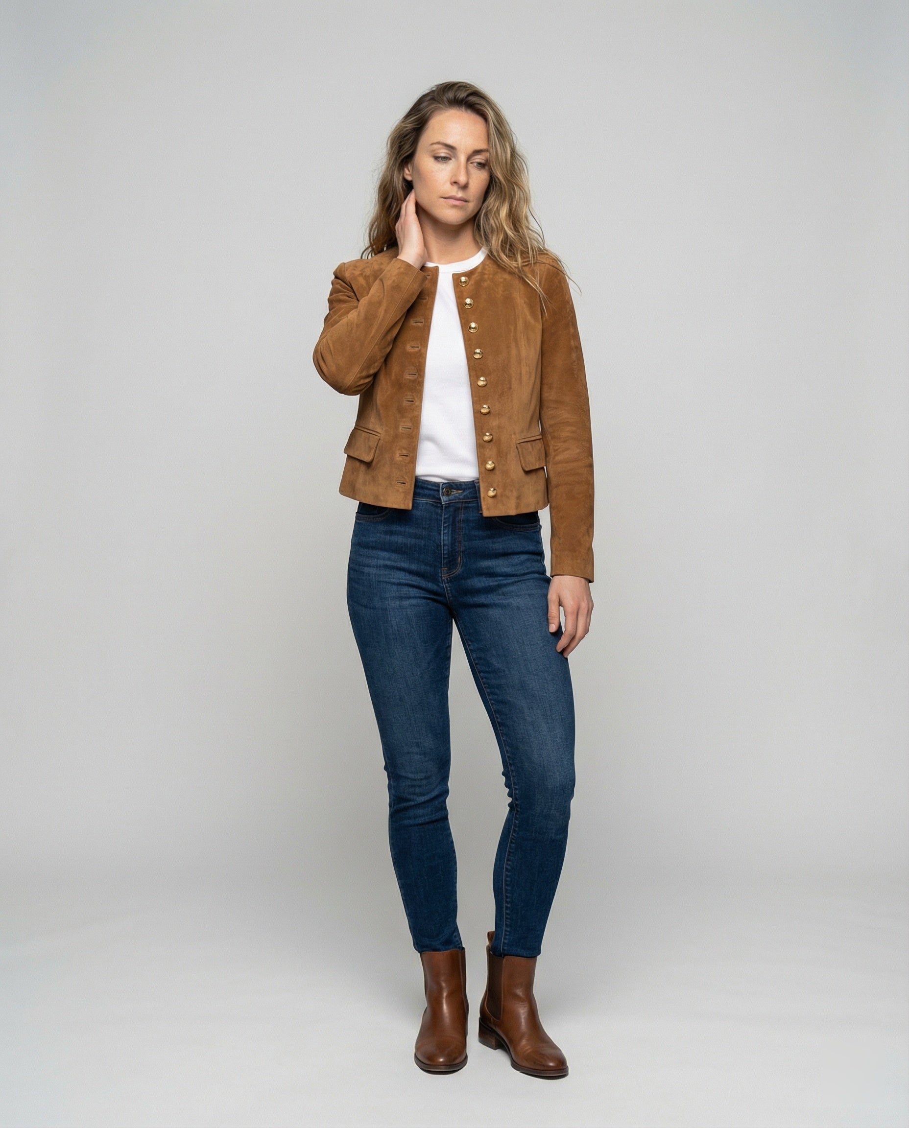 Tan suede jacket featuring a gold button front and a stylish collarless neckline, designed in a cropped tailored fit for a chic, modern look. 1
