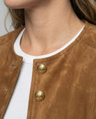 Tan suede jacket featuring a gold button front and a stylish collarless neckline, designed in a cropped tailored fit for a chic, modern look. 3