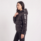Women's black puffer jacket featuring a stylish attached hood, glossy quilted design, and convenient zip pockets, designed for a relaxed fit perfect for winter wear 4