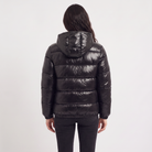 Women's black puffer jacket featuring a stylish attached hood, glossy quilted design, and convenient zip pockets, designed for a relaxed fit perfect for winter wear 5