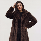 Women's faux fur trench coat featuring double-button fastening, side pockets, and a long relaxed fit, perfect for stylish winter outerwear. 2