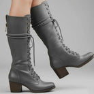 Women's black faux leather knee-high boots featuring a lace-up front, block heel, and stylish stud detail. 3