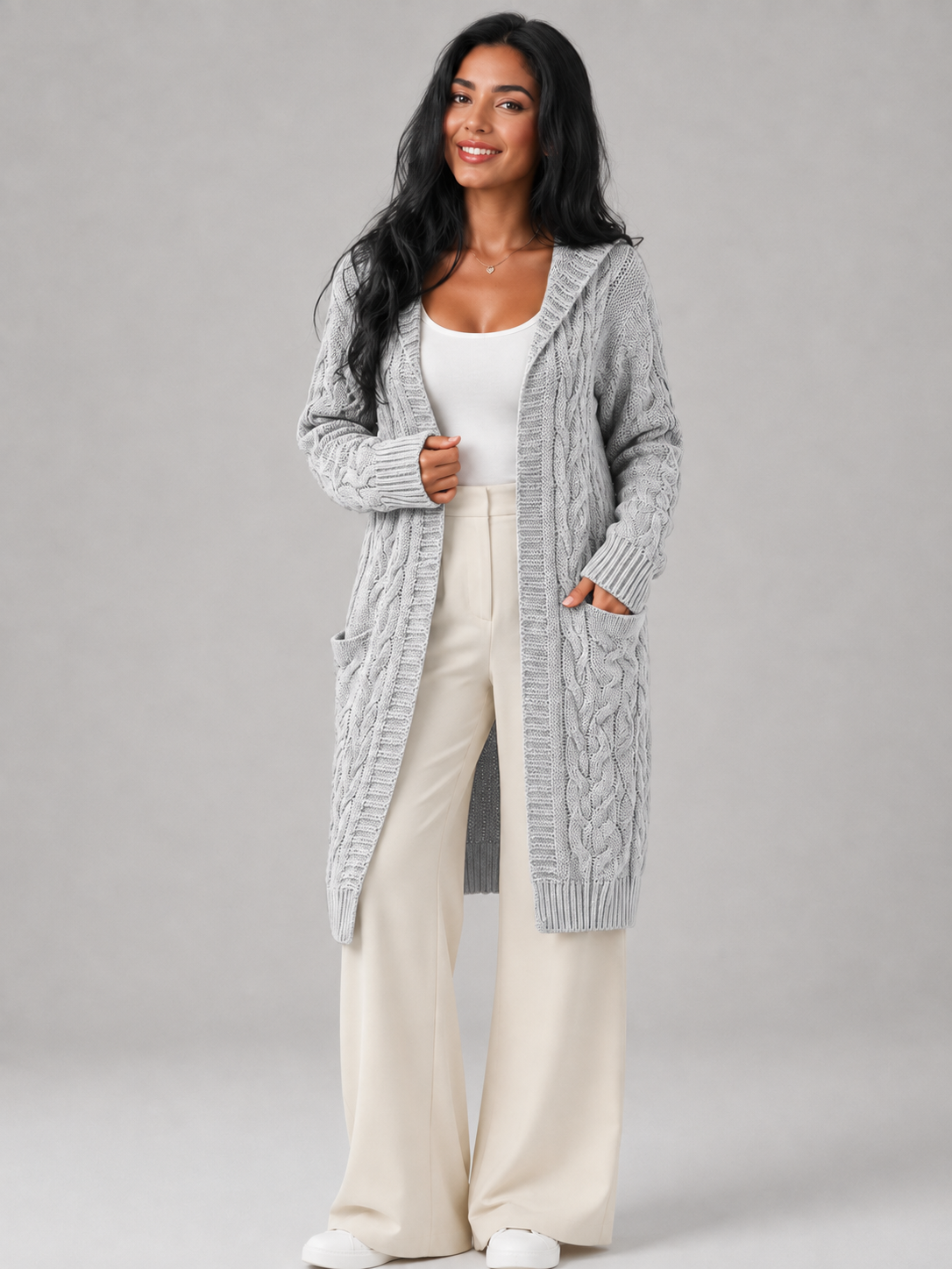 Women's long cardigan sweater featuring a cozy hood and functional pockets, designed with a chunky cable knit pattern and an open front for a stylish and comfortable look. 1