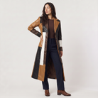 Women's trench coat featuring a stylish patchwork design in faux leather, showcasing a long structured silhouette in brown, black, and white colors. 0