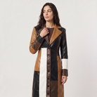 Women's trench coat featuring a stylish patchwork design in faux leather, showcasing a long structured silhouette in brown, black, and white colors. 1