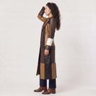 Women's trench coat featuring a stylish patchwork design in faux leather, showcasing a long structured silhouette in brown, black, and white colors. 3