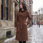 Women's trench coat featuring an adjustable belt, classic lapel collar, and a slim fit longline design in soft faux suede. 1