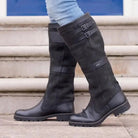 Women's waterproof knee high boots in black vegan leather featuring double buckle straps and an easy pull-on design, perfect for stylish and practical footwear in wet weather. 1