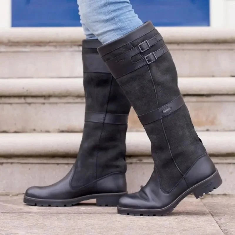 Women's waterproof knee high boots in black vegan leather featuring double buckle straps and an easy pull-on design, perfect for stylish and practical footwear in wet weather. 1
